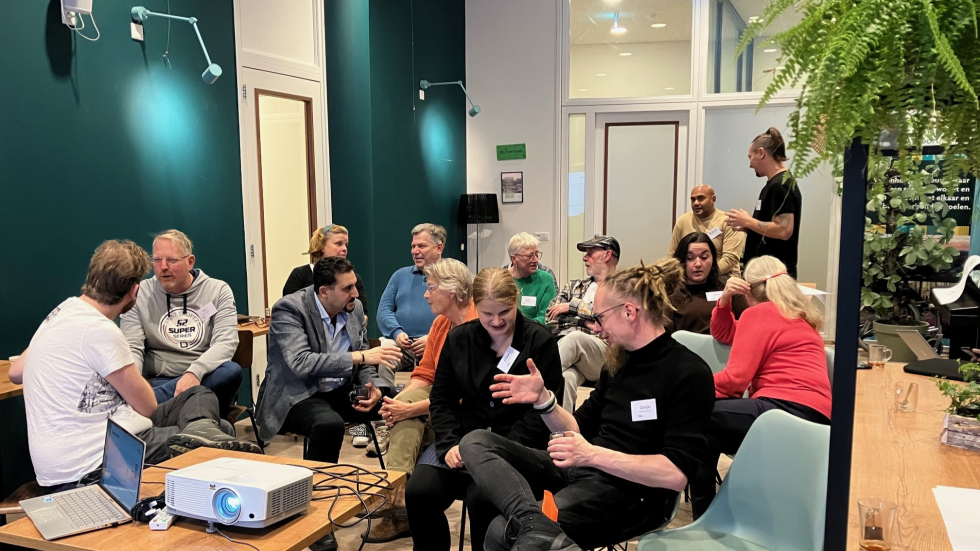 Foto van een groep deelnemers die rond een tafel staan en praten over veiligheid