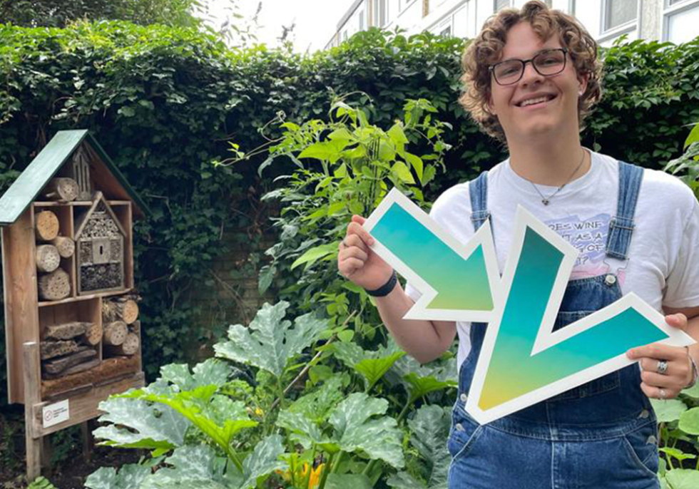 Sander staat voor zijn moestuinbak met een bord in zijn hand met daarop een pijl en een V
