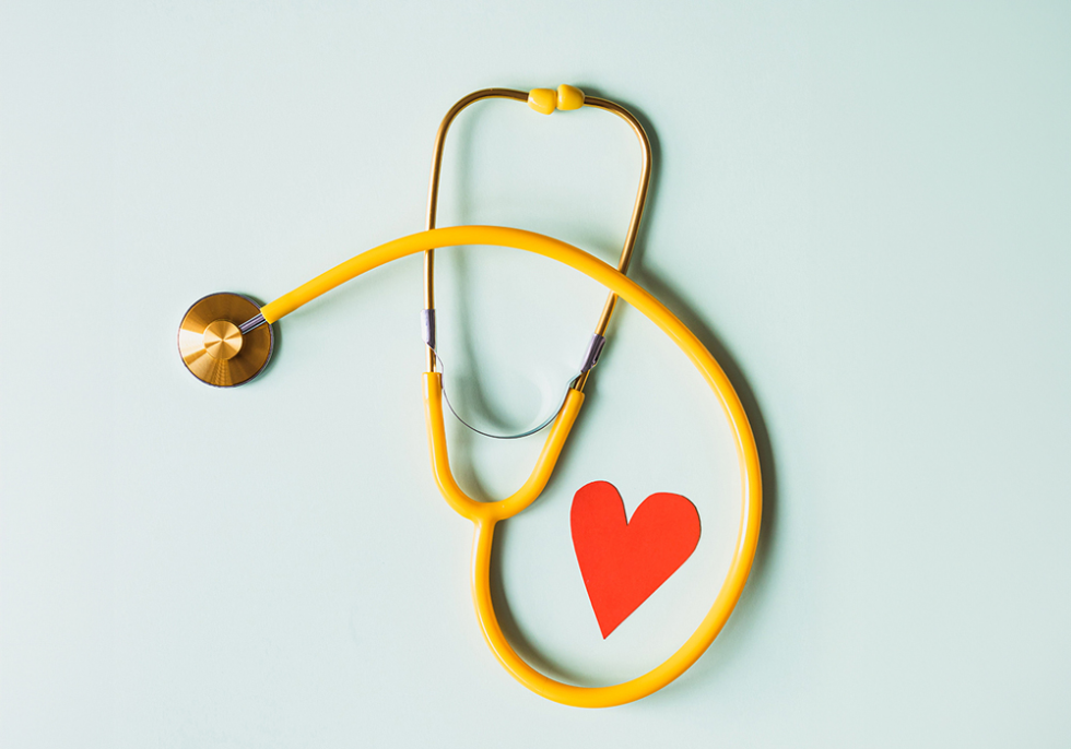 Foto van een gele stethoscoop met een hartje tegen een blauw/groene achtergrond