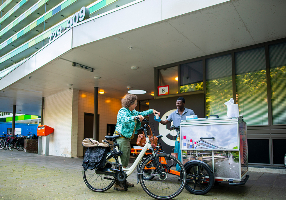 Foto van de soepkar bij de L-flat met iemand die op de fiets langskomt om soep te halen.