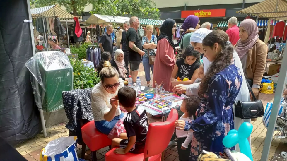 Een kraampje op de braderie met veel bewoners eromheen 